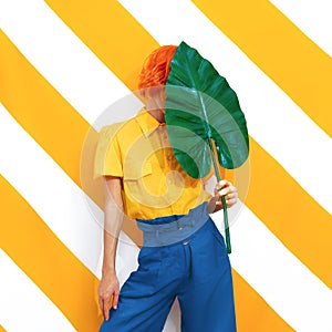 Unrecognizable Model holding palm leaf and wearing vintage look on trendy striped yellow background. Minimal fashion spring summer