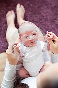 Unrecognizable mother holding newborn baby son in her lap