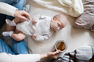 Unrecognizable mother with newborn baby son lying on bed