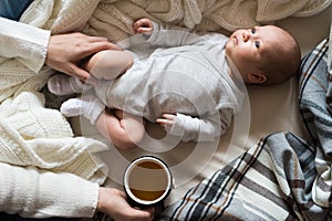 Unrecognizable mother with newborn baby son lying on bed