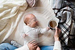 Unrecognizable mother with newborn baby son lying on bed