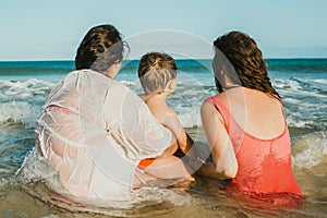 Unrecognizable mothers with son admiring waving sea in summer