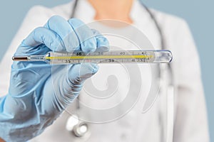 Unrecognizable nurse holds thermometer