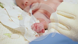 Unrecognizable nurse in white gloves takes action and care for premature baby, selective focus on baby eye. Newborn is