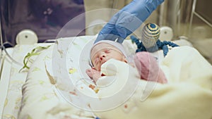 Unrecognizable nurse in white gloves takes action and care for premature baby, selective focus on baby eye. Newborn is