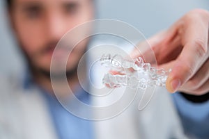 Unrecognizable orthodontist holding invisible dental aligners.