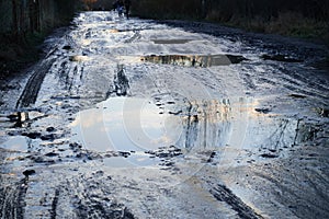 unrecognizable pedestrians walk cautiously along the broken dirt road. The coating is slippery, wet, liquid