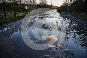 Unrecognizable pedestrians walk cautiously along the broken dirt road. The coating is slippery, wet, liquid