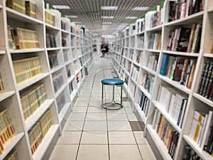 Unrecognizable people, bookshelves with books, bookshelves in bookstore. Empty chair for readers. Concept interesting