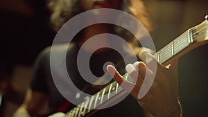 Unrecognizable person playing guitar in studio. Man hand pinching chords indoor.