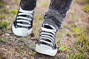 Unrecognizable person in rubber shoes walks on footpath, front view