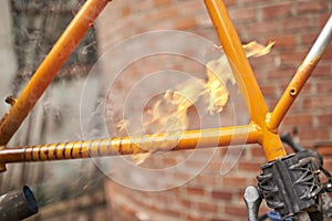 Unrecognizable person using a blowtorch to remove the paint of a bicycle frame