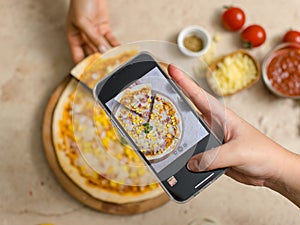 Unrecognizable person using smartphone taking photo top view shot of delicious tasty juicy corn and ham cheesy pizza placed on