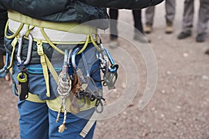 Unrecognizable person wearing a mountaineering harness with carabiners hanging