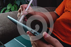 Unrecognizable person working on the sofa with his tablet and an electronic pen