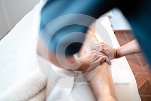 Unrecognizable physiotherapist making a tibia massage to a female patient. Wellness center spa. Skin care