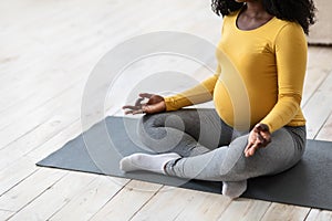 Unrecognizable pregnant lady meditating at home or fitness studio