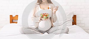 Unrecognizable pregnant woman eating vegetable salad in bed