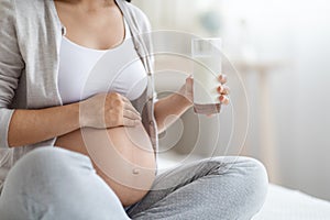 Unrecognizable pregnant woman holding glass of milk