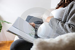 Unrecognizable pregnant woman looking at photo album