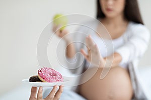 Unrecognizable pregnant woman saying no to unhealthy food