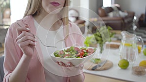 Unrecognizable pretty girl enjoying fresh organic salad. Blond young Caucasian woman eating healthful vegan dish. Weight