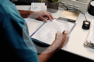 Unrecognizable Radiographer Filling Medical Card At Workplace