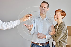 Unrecognizable real state agent giving new house key to young happy couple