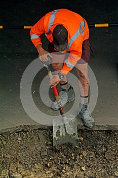 Road worker digging with shovel