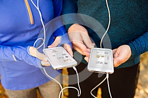 Unrecognizable running couple with smart phones and earphones