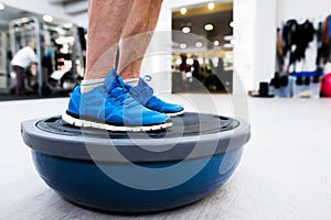 Unrecognizable senior man in gym standing on bosu balance ball