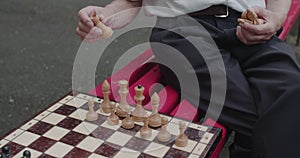 Unrecognizable senior man putting a chess on board during a game with partner