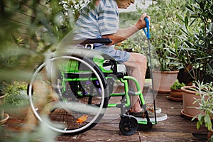 Unrecognizable senior man in wheelchair doing exercise on terrace.