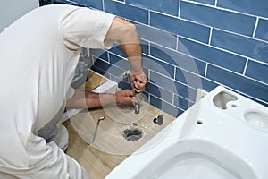 Unrecognizable senior plumber installer installing toilet drain flange.