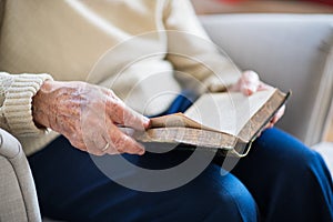 A senior woman reading Bible at home at Christmas time.