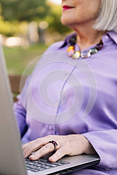 unrecognizable senior woman typing on laptop