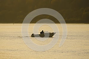 Unrecognizable silhouette of a fisherman on a boat.