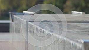 Unrecognizable skater does the grind trick crooked on granit ledge, closeup view