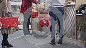 Unrecognizable slim woman joining queue standing at cashier in hardware store. Men and women buying tools and building