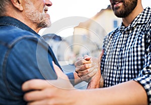 Unrecognizable son and his overjoyed senior father in town, greeting.