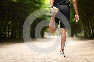 Unrecognizable sportsman stretching legs, jogging in park