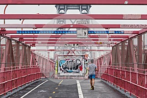 Unrecognizable sporty recreational male runner funning at Williamsburg bridgein New York City, USA