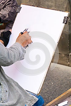 Unrecognizable street artist. Hand of a cartoonist holding a marker pen on a blank canvas
