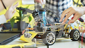 Unrecognizable students assembling car in robotics class