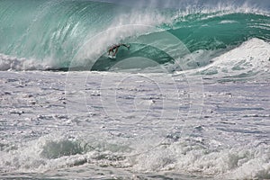 Unrecognizable surfer coming partially into view while in the curl of a masiive wave.