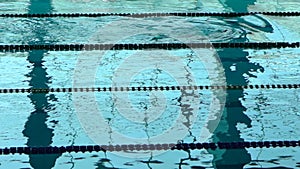 Unrecognizable swimmer silhouette in the pool with blue water and dividers of swimming tracks