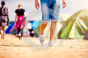 Unrecognizable teenage couple, tent festival, sunny summer, legs