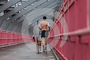 Unrecognizable topless recreational runner and a dog at Williamsburg bridgein New York CIty, USA.