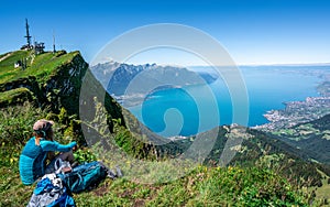 Unrecognizable tourist hiker admiring the aerial view of Lake Geneva from Rochers-de-Naye mountain summit in Switzerland