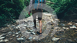 Unrecognizable Traveler Man With Backpack Walks Along Mouth Of Mountain River In Forest, Rear View. Trek Hiking Destination Experi